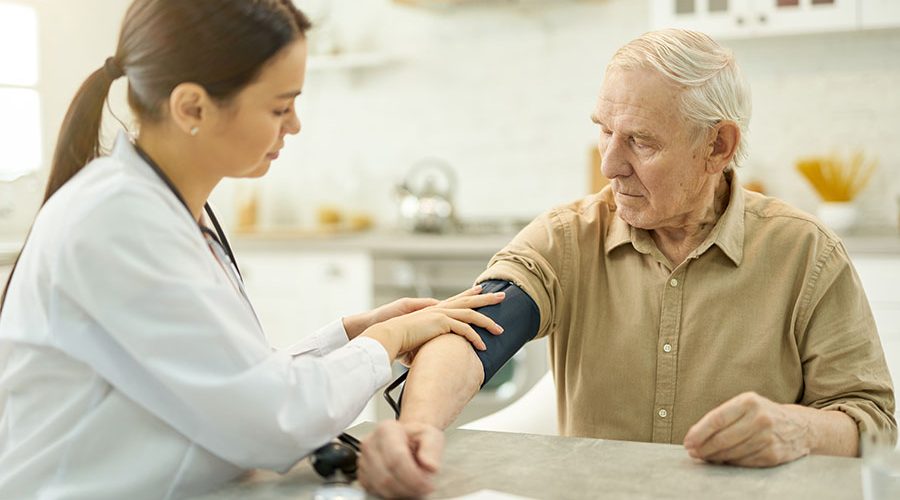 Attentive medic preparing to measure elderly man blood pressure